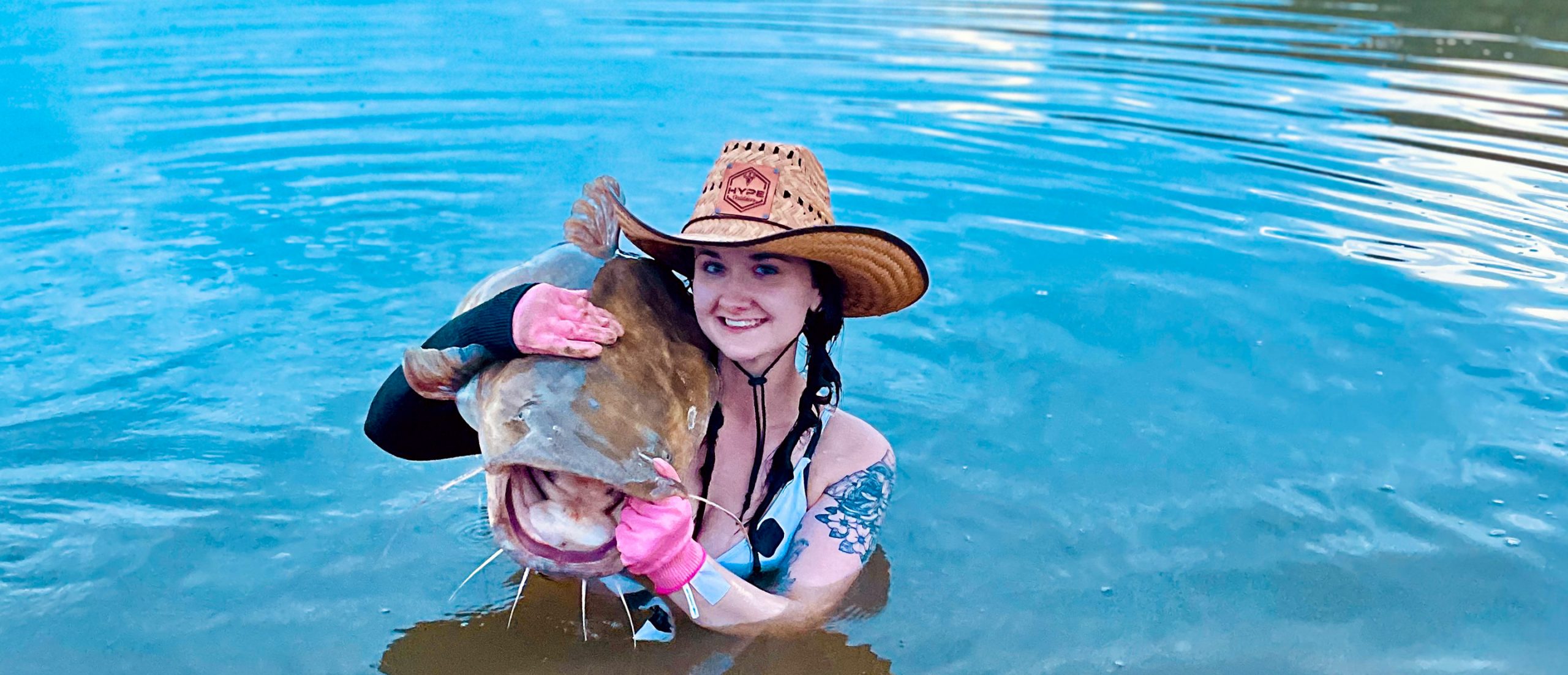 woman in a lake or stream with a catfish on her shoulder