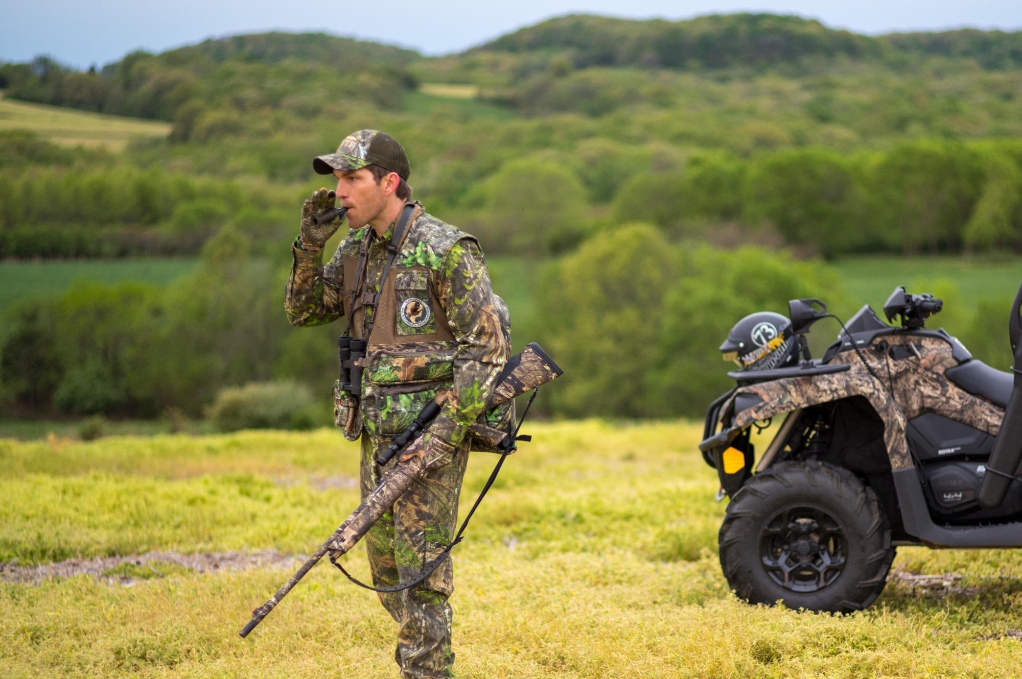 turkey hunter using a locator call with a four wheeler in the background