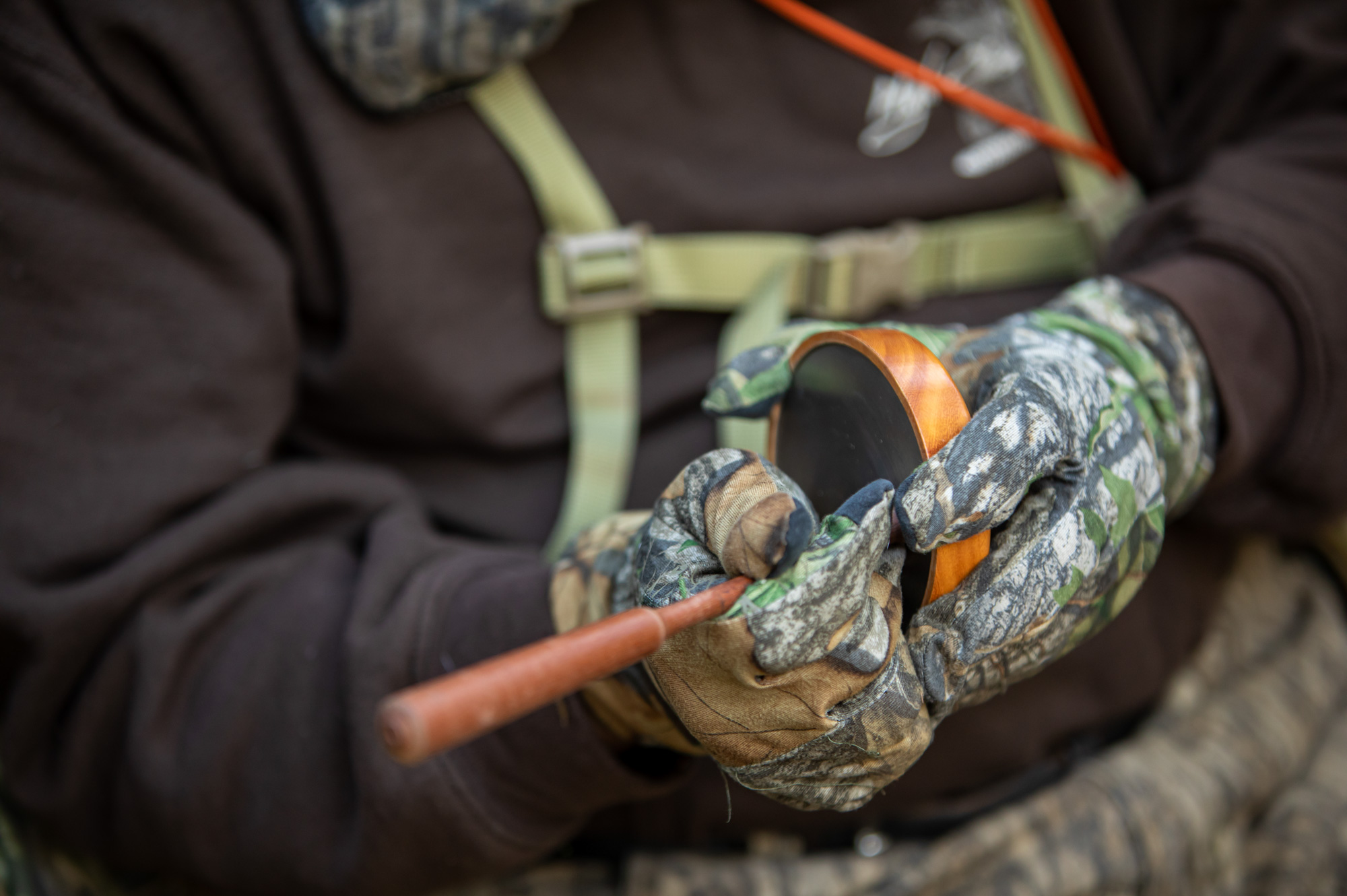 a close-up photograph of turkey hunter using a pot call