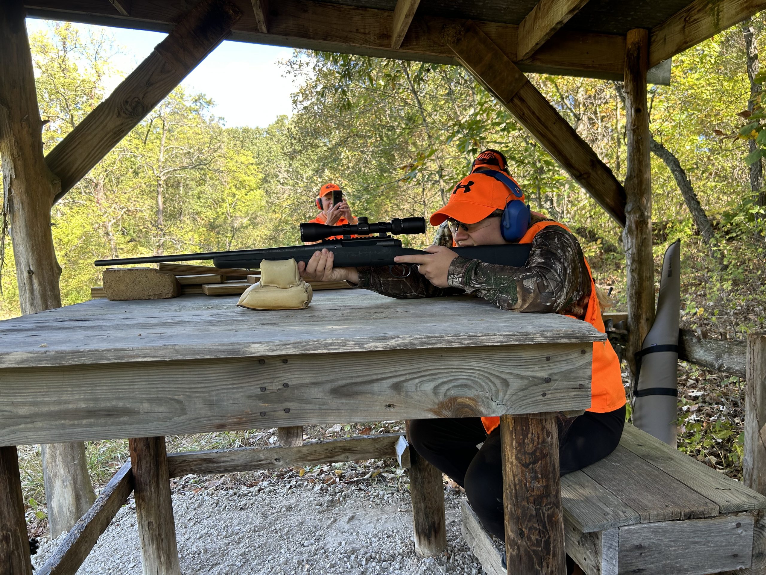 woman looks down the sights of a rifle on the shooting range.